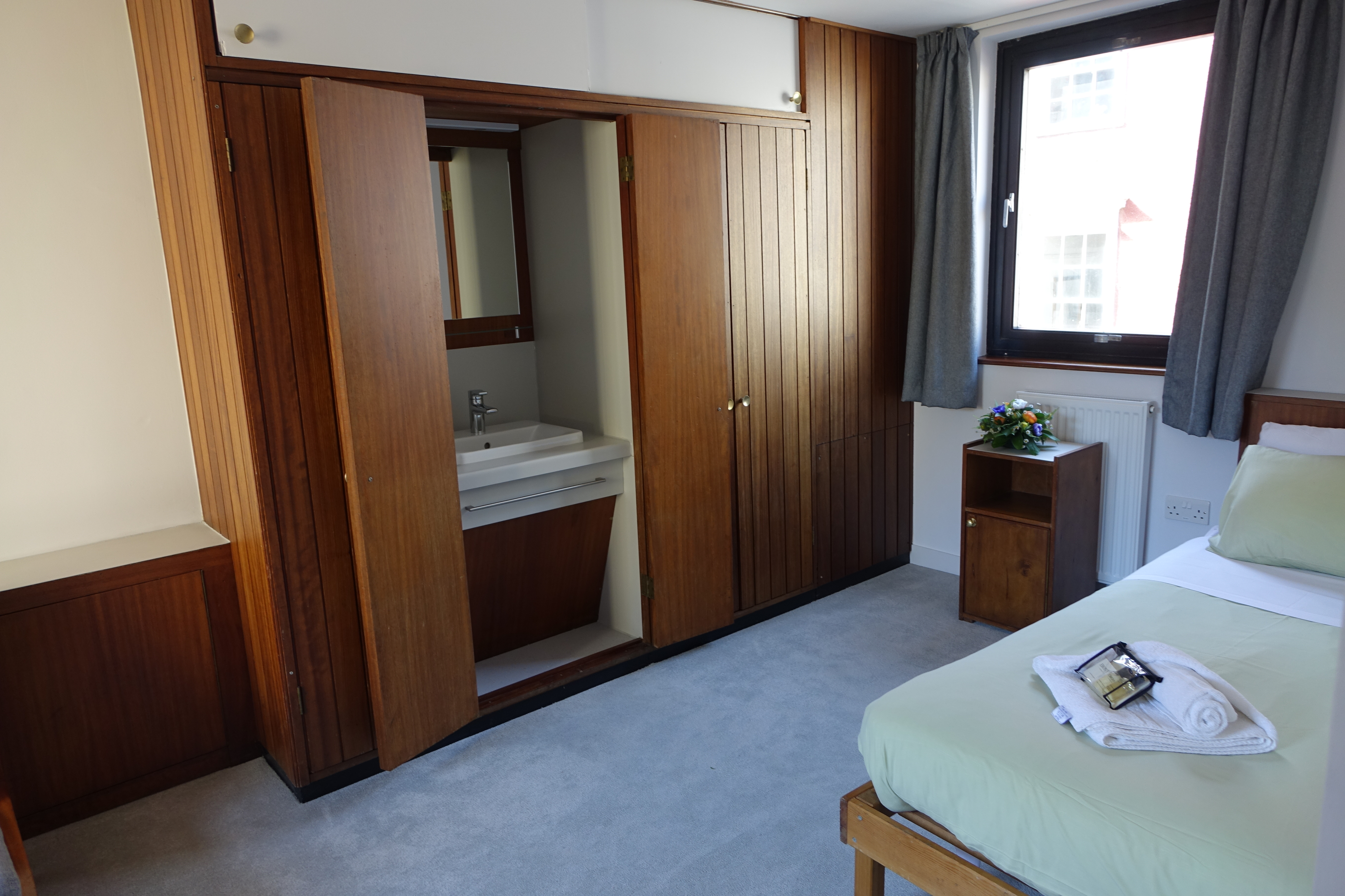 A standard single bedroom with wash hand basin