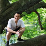 An Exeter College Summer Programme Student sitting on a branch of a tree