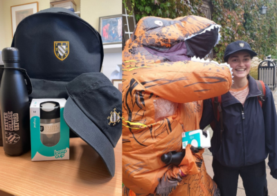 Giving Day Raffle prizes and Exeter's Giving Day mascot TRexeter with a student holding giving day raffle prizes
