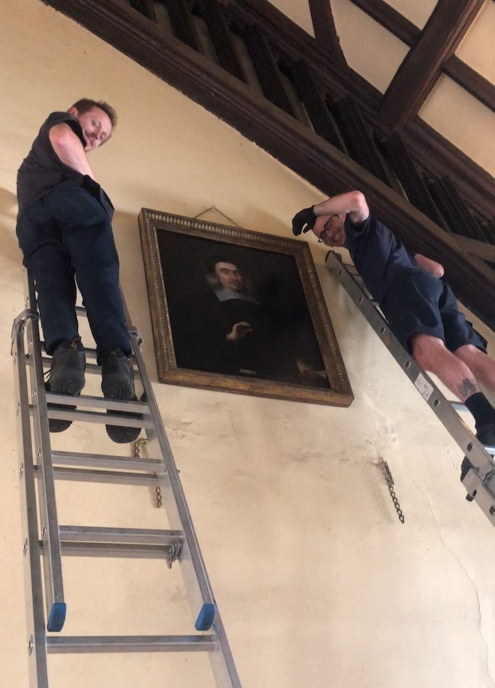 Team members from Gander & White re-hanging the Portrait of John Conant in the dining hall