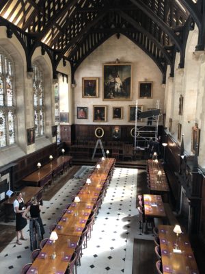 Georgie Dennis and Alexandra Earl observing the rehanging of the portraits in the dining hall