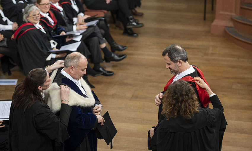 The outgoing and incoming Junior Proctors swap hoods