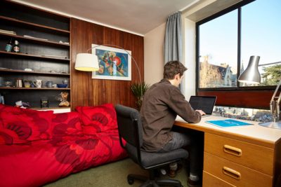 student sat at a desk in a typical student bedroom.