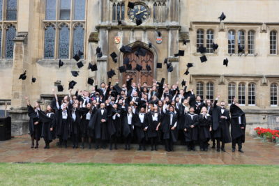Exeter College graduates throwing their mortar boards in the air.