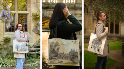 A three-panel collage of people modelling cream-colored canvas tote bags with black architectural illustrations in a historic courtyard setting. Left panel: A smiling person wearing glasses, a beige coat, scarf, and light blue jeans stands beside blooming purple wisteria while holding a tote bag printed with a detailed building sketch. They are also holding a colorful book. Center panel: A person in a dark green coat is photographed from behind beside a river, carrying a tote bag featuring a detailed drawing of a bridge and riverside buildings. Warm reflections shimmer on the water in the background. Right panel: A person in a beige coat stands in profile carrying a tote bag printed with an intricate arched ceiling illustration. Trees and stone architecture frame the softly blurred background.