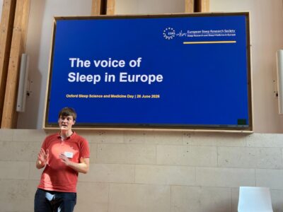 Dr Lukas Krone in front of a screen displaying “The voice of Sleep in Europe” at Oxford Sleep Science and Medicine Day 2026.
